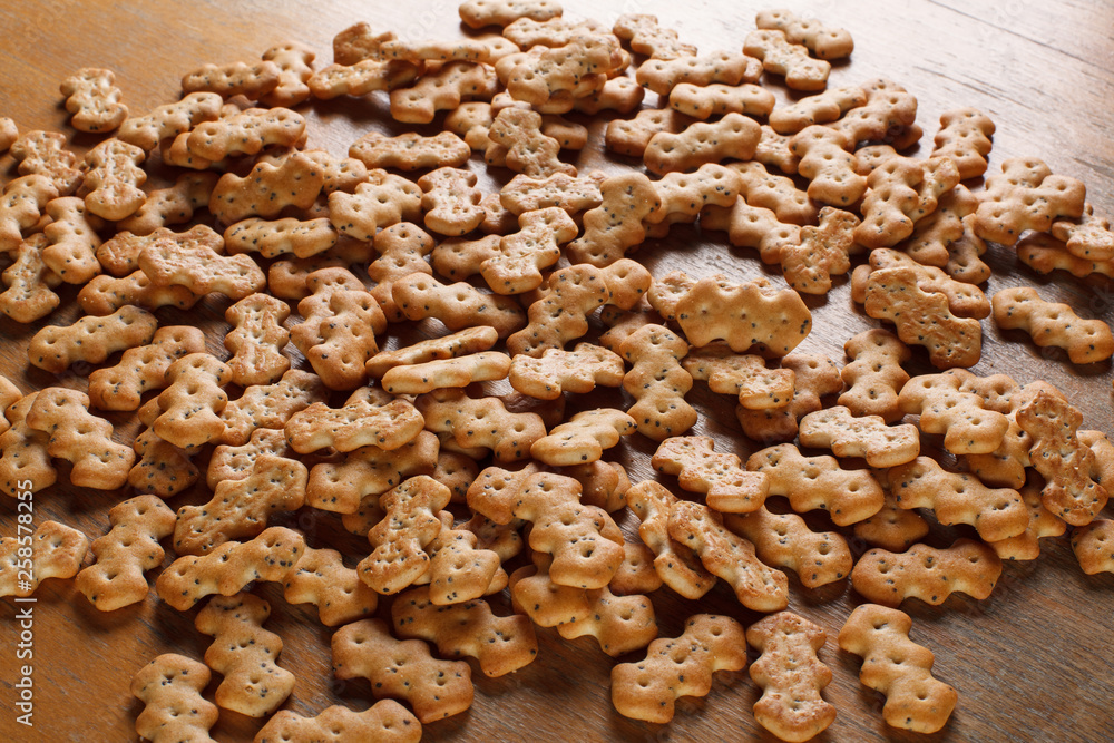 Composition of crackers with poppy seeds, spread out on a wooden background Composition of crackers with poppy seeds, spread out on a wooden background
