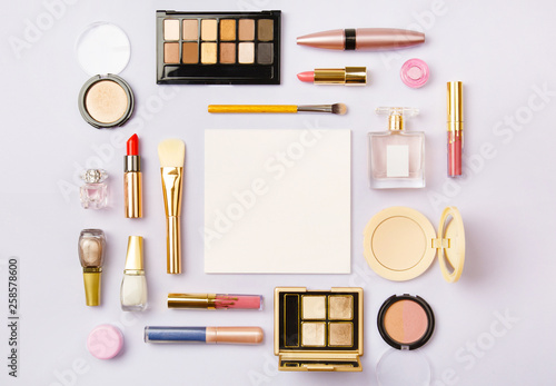 woman make up cosmetics on purple. Decorative cosmetics: highlighter, concealer, rouge, palette with eye shadows and brushes for face make up, face sculpture. Copy space. Gold and purple
