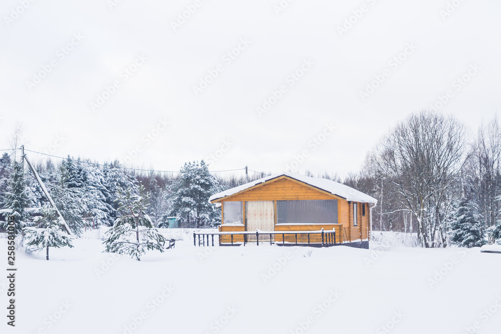 A typical suburban two-storey wooden house, the cottage near the forest in winter A typical suburban two-storey wooden house, the cottage near the forest in winter