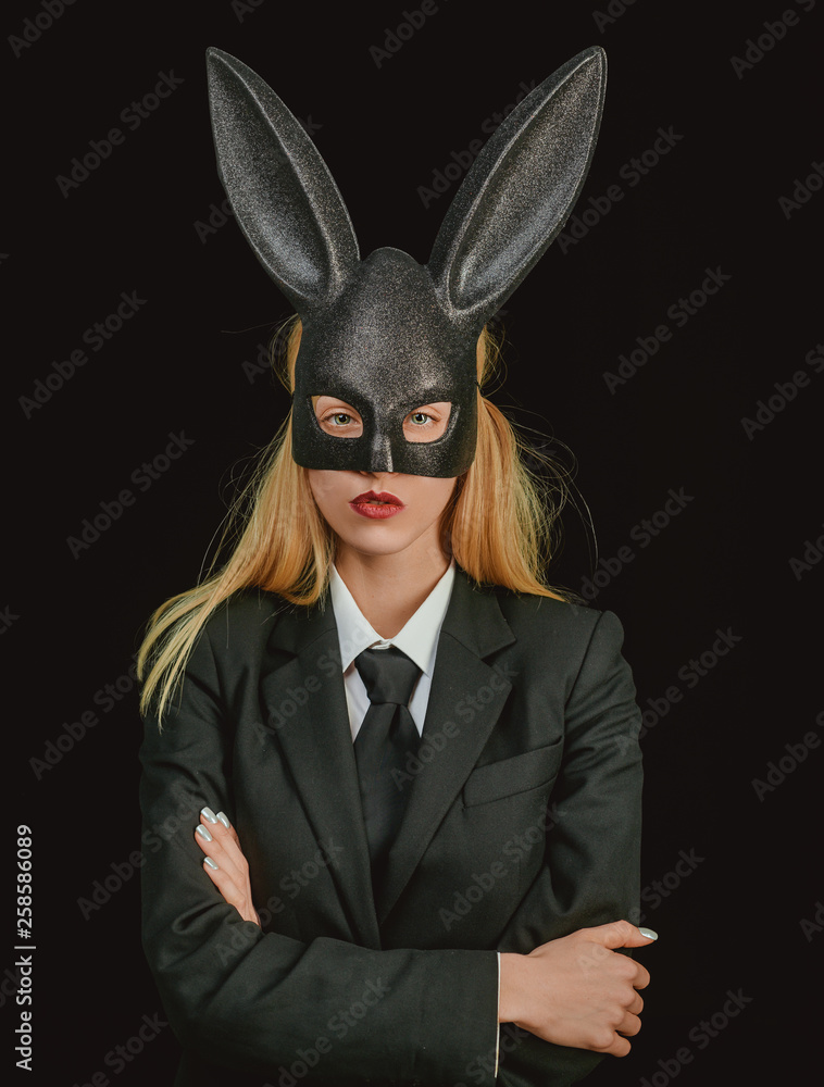 Easter woman. Sexy woman with mask Easter bunny on a black background and looks very sensually. Happy woman in bunny ears with easter egg.