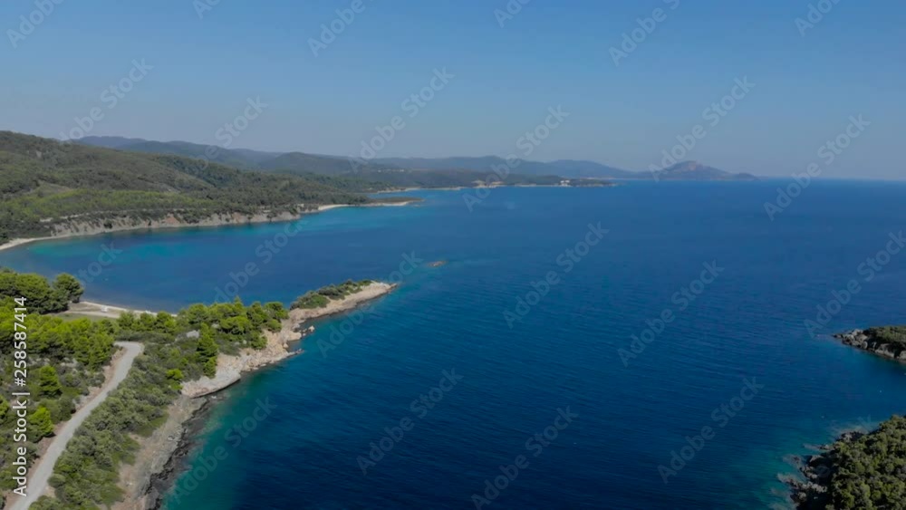 Aerial drone view of blue sea surface surrounded with trees. Top view of dark blue ocean water surface, seashore, forest, car road. Aerial drone view of blue sea surface surrounded with trees. Top view of dark blue ocean water surface, seashore, forest, car road.
