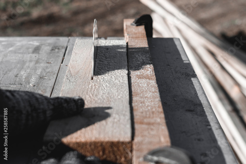 saw blade. car saws wood. there is a blackboard in the background. working hand