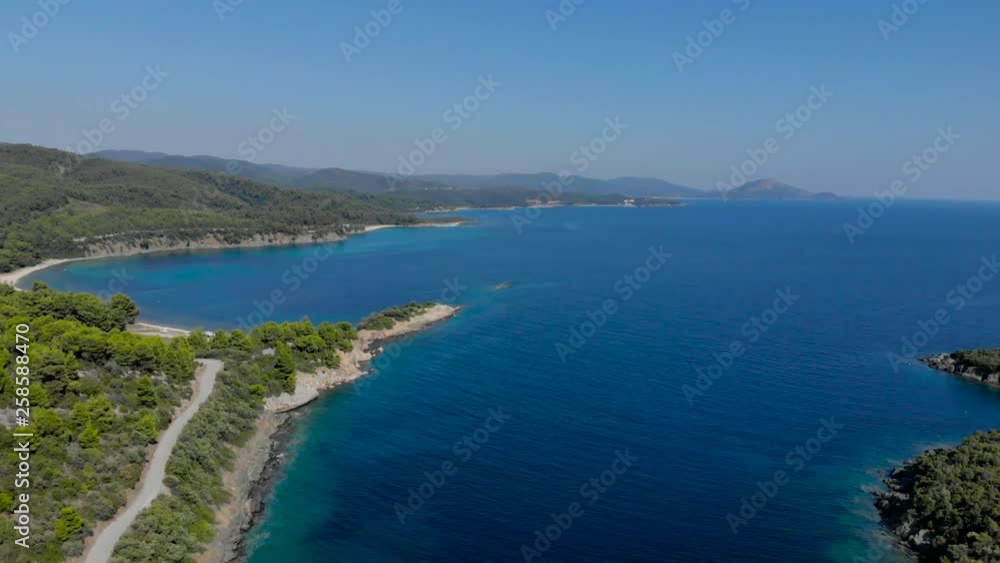 Aerial drone view of blue sea surface surrounded with trees. Top view of dark blue ocean water surface, seashore, forest, car road. Aerial drone view of blue sea surface surrounded with trees. Top view of dark blue ocean water surface, seashore, forest, car road.