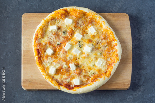 Pizza 4 cheese: gorgonzola (dor blue), mozzarella, emental and parmesan. On a dark gray background with copy space photo