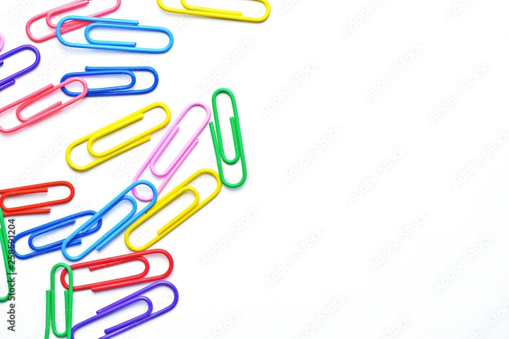 Various colored paper clips lie across a white surface - a background consisting of a white base and colorful paperclips Various colored paper clips lie across a white surface - a background consisting of a white base and colorful paperclips