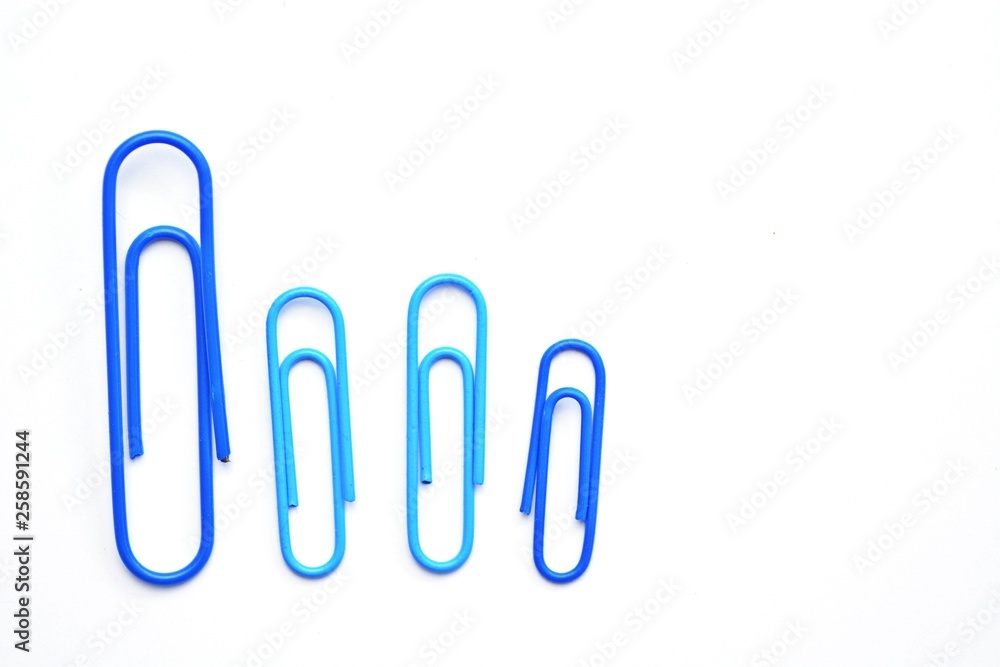 Various colored paper clips lie across a white surface - a background consisting of a white base and colorful paperclips Various colored paper clips lie across a white surface - a background consisting of a white base and colorful paperclips