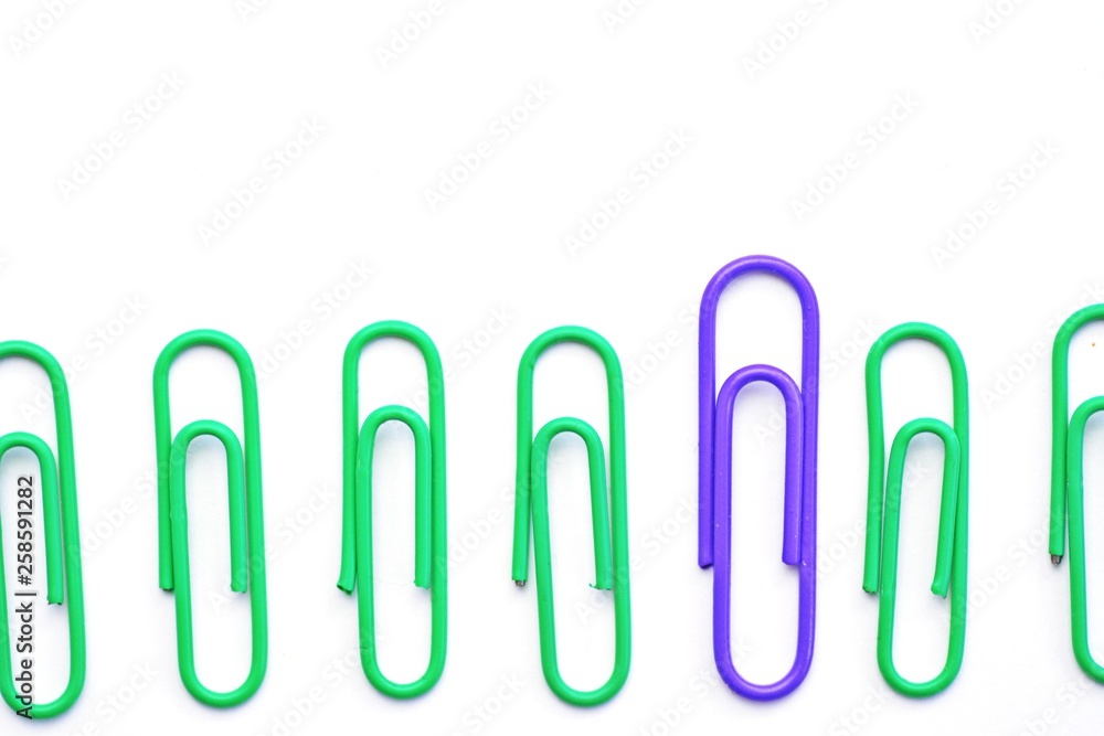 Various colored paper clips lie across a white surface - a background consisting of a white base and colorful paperclips Various colored paper clips lie across a white surface - a background consisting of a white base and colorful paperclips