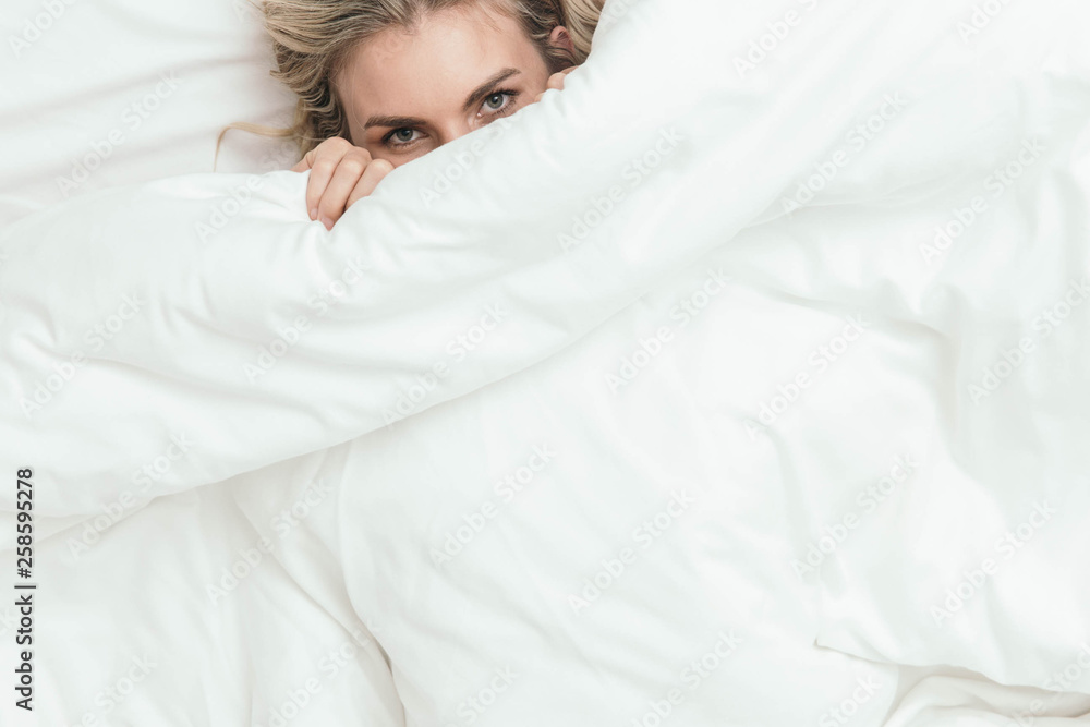 Happy Caucasian Blonde Girl Peeking from Under White Duvet Covers Happy Caucasian Blonde Girl Peeking from Under White Duvet Covers