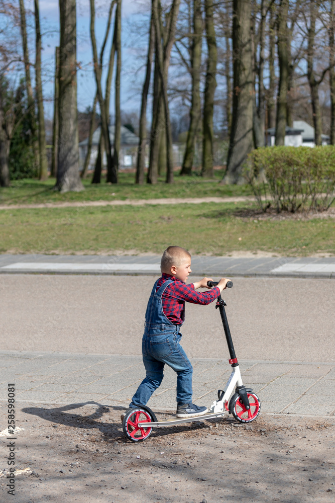 little boy play balance scooter at spring in park little boy play balance scooter at spring in park