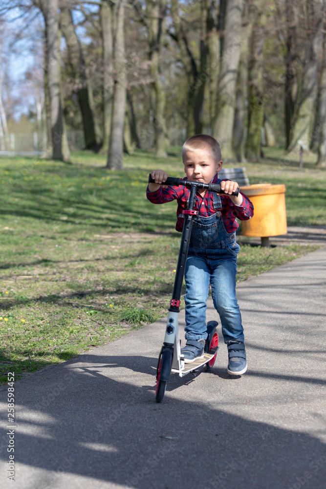 Obraz premium little boy play balance scooter at spring in park