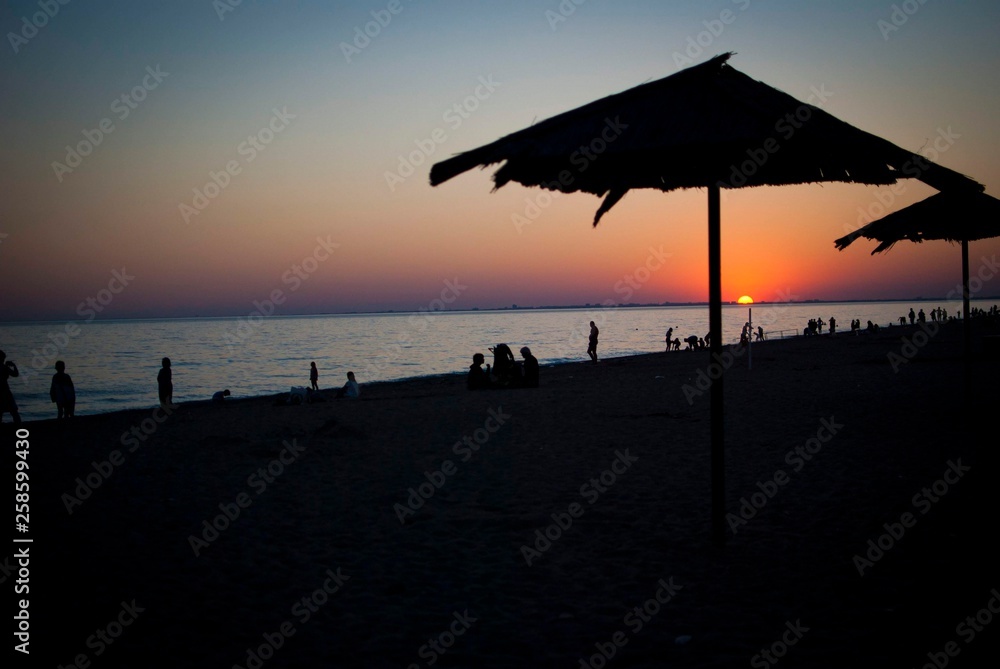 Silhouette on the beach with sunset on the sea with umbrella.