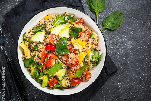 Quinoa salad with fresh vegetables on black.