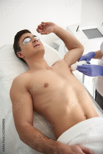 Waist up laser epilation procedure of man armpit