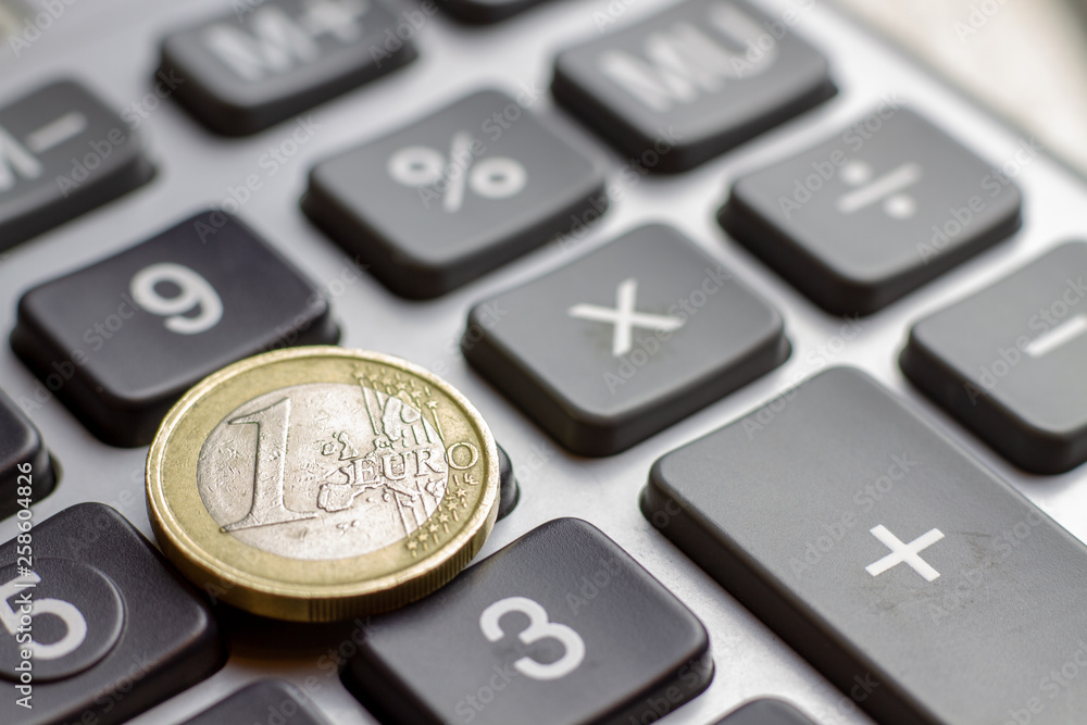 Keyboard calculator closeup with one euro coin. Business concept of economy finance loan collateral mortgage loan rates increase.