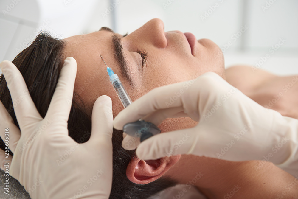 Man on beauty injection procedure of forehead skin Man on beauty injection procedure of forehead skin