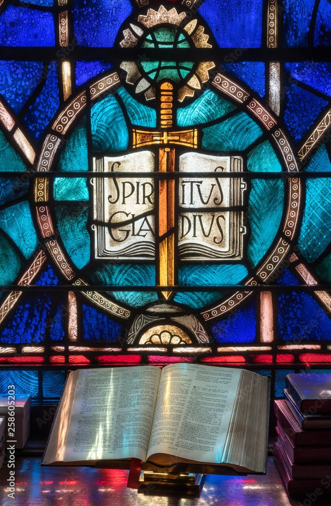 Colored light from stained glass window in methodist church falls across open bible