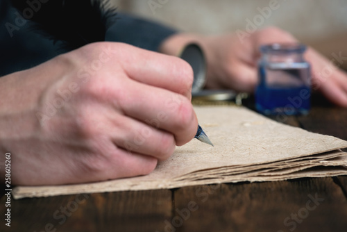 A writer with a quill pen in hand is writing a book by a desk.