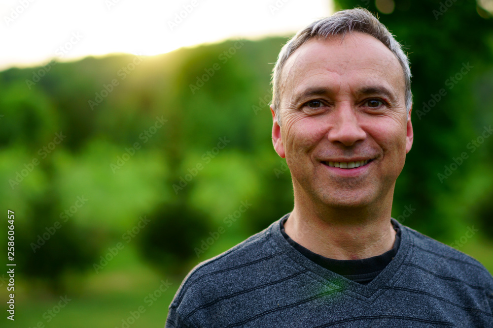 A caucasian man, 50's, is happy and smiling, at sunset, in his rural backyard. A caucasian man, 50's, is happy and smiling, at sunset, in his rural backyard.