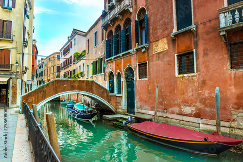 Canal with boats and colorful facades of old medieval houses and bridge in Venice, Italy, Europe © offcaania