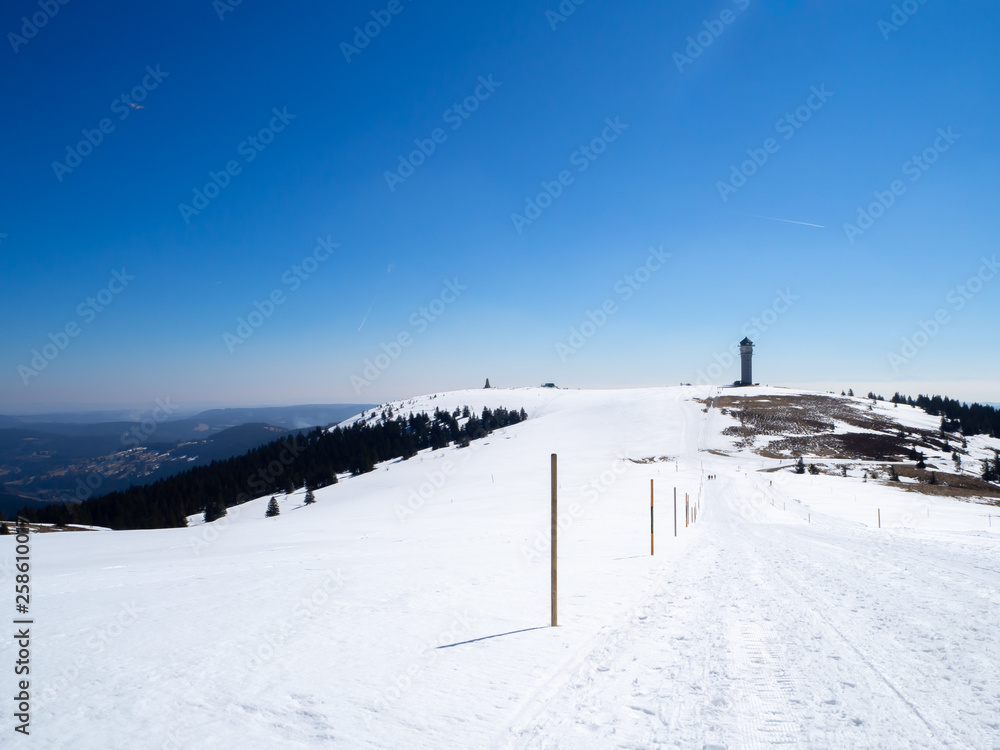 Panoramic view on snowy hill in the black forest with tower in the background and blue sky - Ski resort 