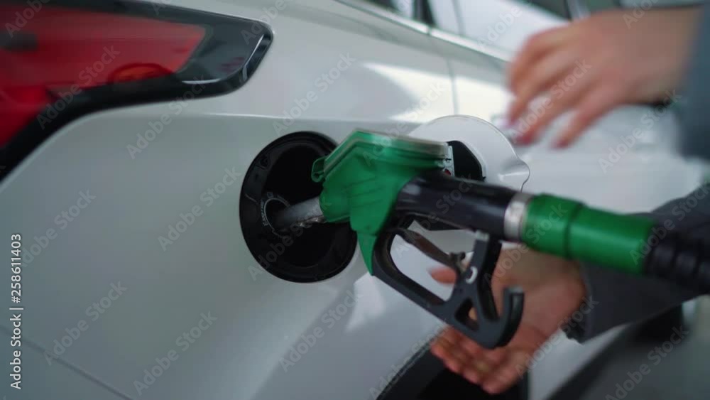 Woman fills petrol into her car at a gas station closeup Woman fills petrol into her car at a gas station closeup