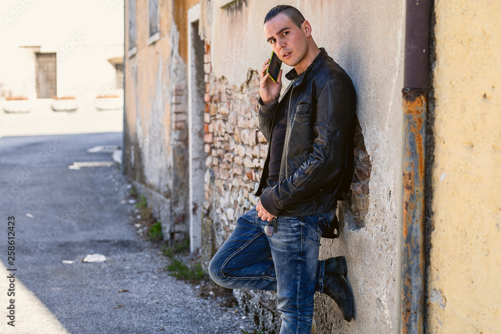 Half length portrait of male with style using cell telephone while standing in urban setting Half length portrait of male with style using cell telephone while standing in urban setting
