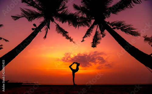 Beautiful young woman practic yoga at the beach. Early morning exercise. Sunrise photo