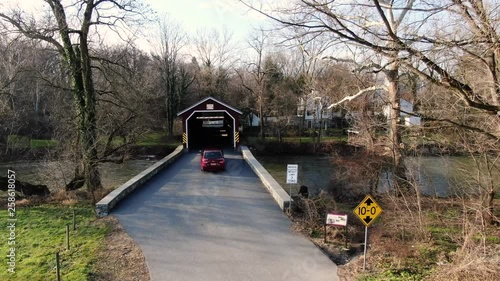 Aerial a red car drives through the Pinetown Bushong's Mill Covered Bridge Lancaster County, Pennsylvania. Concept: traditional,Amish,transportation photo