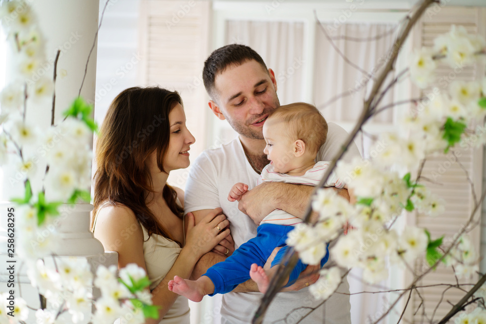 Obraz premium Loving parents affectionately cradling adorable baby son in their arms looking at him. Childhood, parenthood, togetherness, love, happiness concept