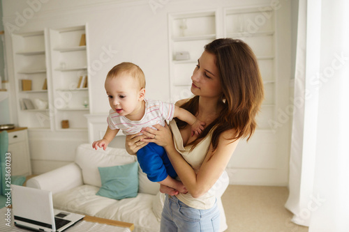 Mother playing with baby boy in living room. Happy parent and son having fun indoor. Cheerful sweet kid portrait, mom and child. 