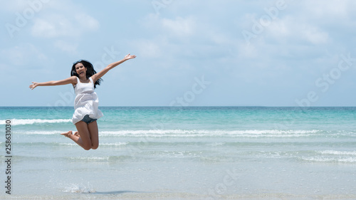 Beautiful young Asian woman are jumping and show hand in to sky relaxing on beach on summer holidays vacations. Concept freedom, Lifestyle, tourism, holiday. with copy space