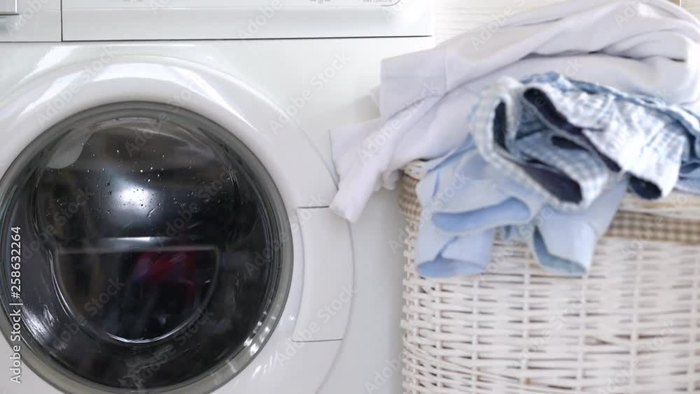 Laundry is washed in the washing machine, and clean things are on the basket nearby. Laundry is washed in the washing machine, and clean things are on the basket nearby.