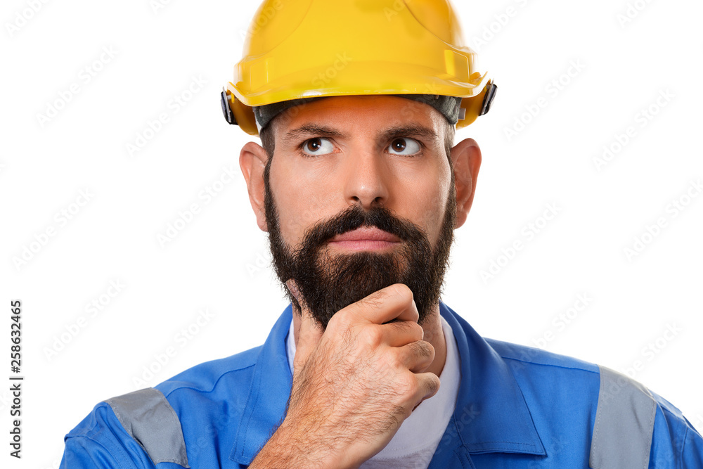Thoughtful bearded builder in hard hat, foreman or repairman in the helmet. Close up portrait architect builder, civil engineer working over white background Thoughtful bearded builder in hard hat, foreman or repairman in the helmet. Close up portrait architect builder, civil engineer working over white background