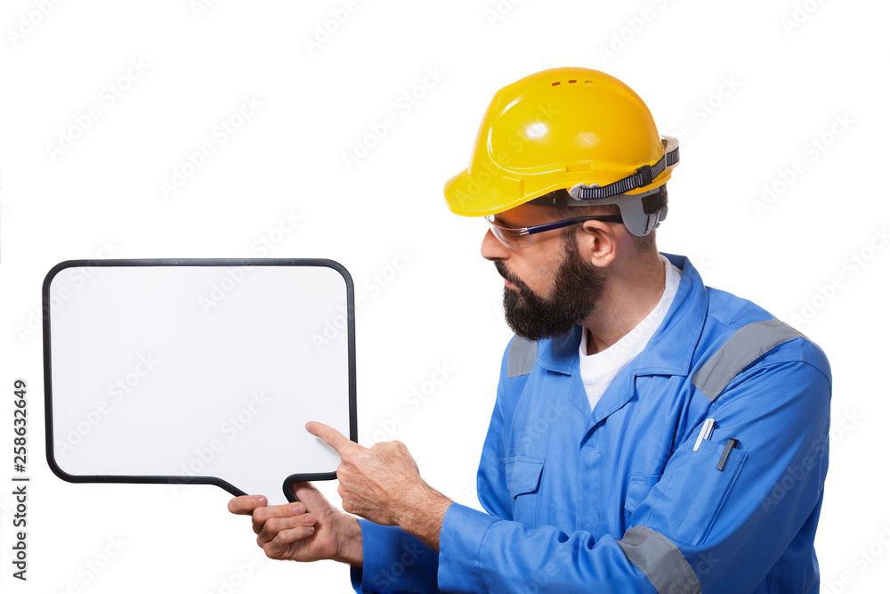 Bearded worker in protective construction helmet pointing to the white chalk board with copyspace, isolated Bearded worker in protective construction helmet pointing to the white chalk board with copyspace, isolated
