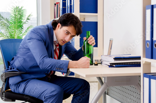Young businessman employee drinking in the office 