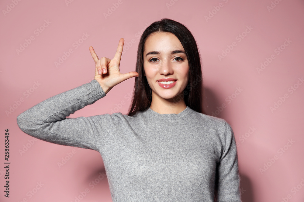 Woman showing I LOVE YOU gesture in sign language on color background Woman showing I LOVE YOU gesture in sign language on color background