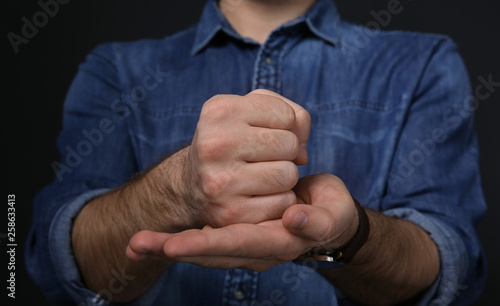 Man showing word CRUCIFY in sign language on black background, closeup
