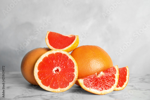 Fresh tasty grapefruits on table against light background
