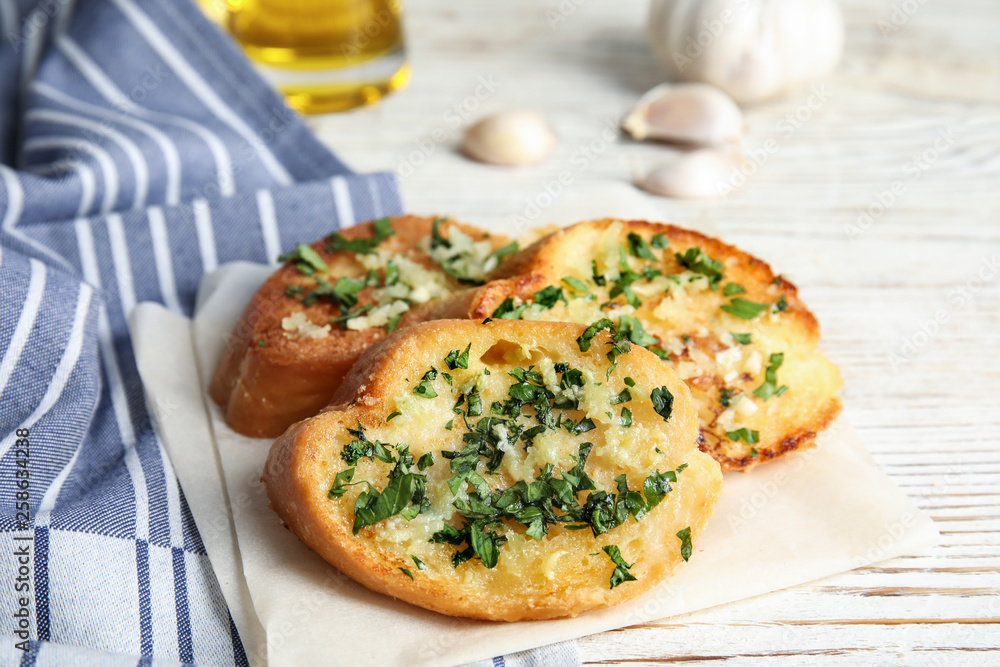 Slices of tasty garlic bread with herbs on table Slices of tasty garlic bread with herbs on table