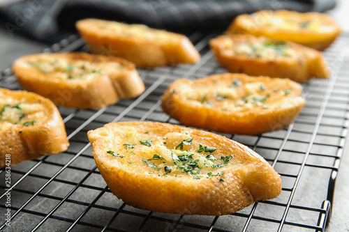 Baking rack with tasty homemade garlic bread on table, closeup © New Africa