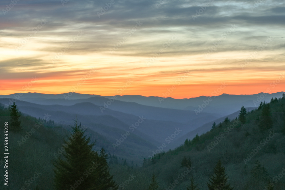 Orange glow from the sun illuminates the sky over the Great Smoky Mountains