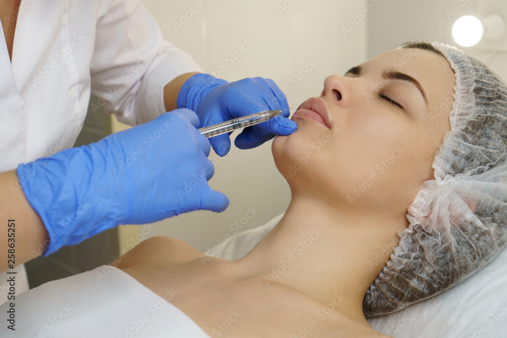 Aesthetic cosmetology. Facelift in the spa salon. Beautician makes injections girl in lips. Smoothing of mimic wrinkles. Close-ups Aesthetic cosmetology. Facelift in the spa salon. Beautician makes injections girl in lips. Smoothing of mimic wrinkles. Close-ups