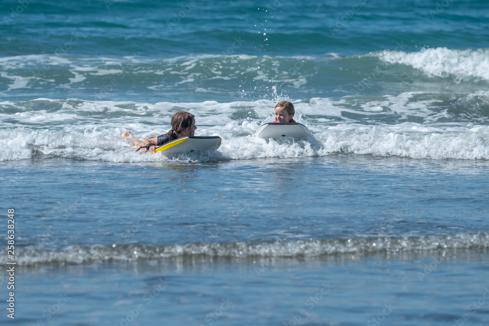 Two sisters having fun while body boarding in the sea Two sisters having fun while body boarding in the sea