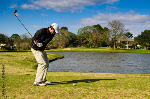 Golfer in action shot hitting with moving ball in frame on tee
