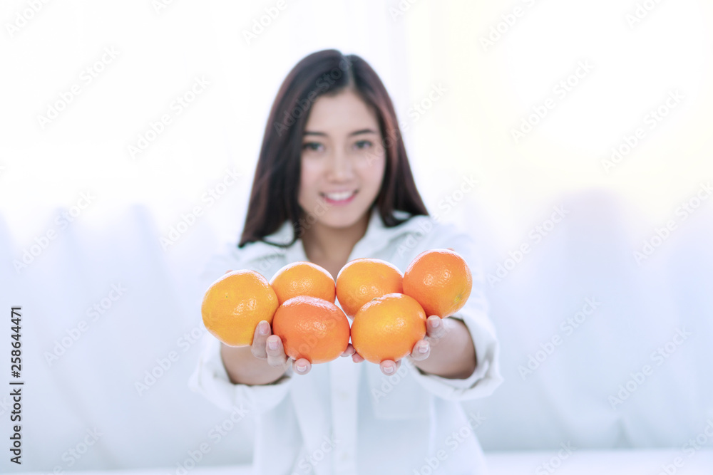 Lifestyle and healthy food concept. Focus hands of smile young woman holding fresh oranges fruit in her hand on white bed at home with copy space. Focus oranges fruit. Lifestyle and healthy food concept. Focus hands of smile young woman holding fresh oranges fruit in her hand on white bed at home with copy space. Focus oranges fruit.