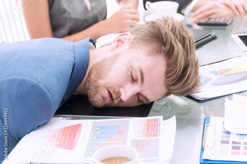 Businessman wear blue suit with white coffee sleeping at white office desk breakdown looking tired. Business people working overtime headache.