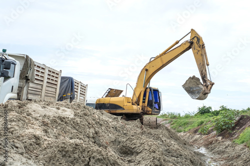 Excavator loading sand onto dumper truck at a sand quarry.