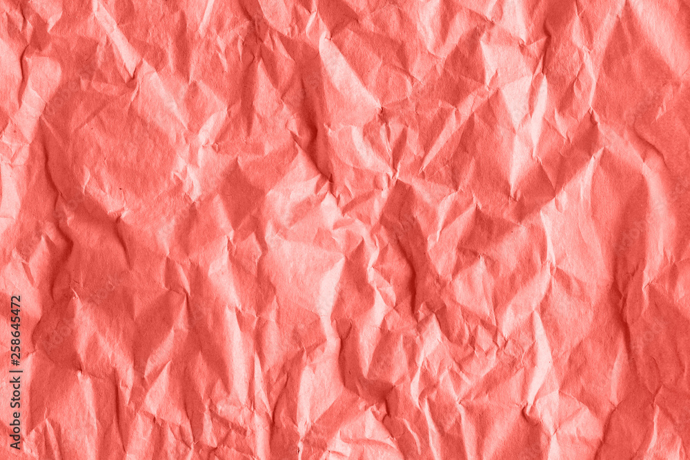 Fototapeta premium Texture of crumpled rough wrapping paper in coral toned, abstract background