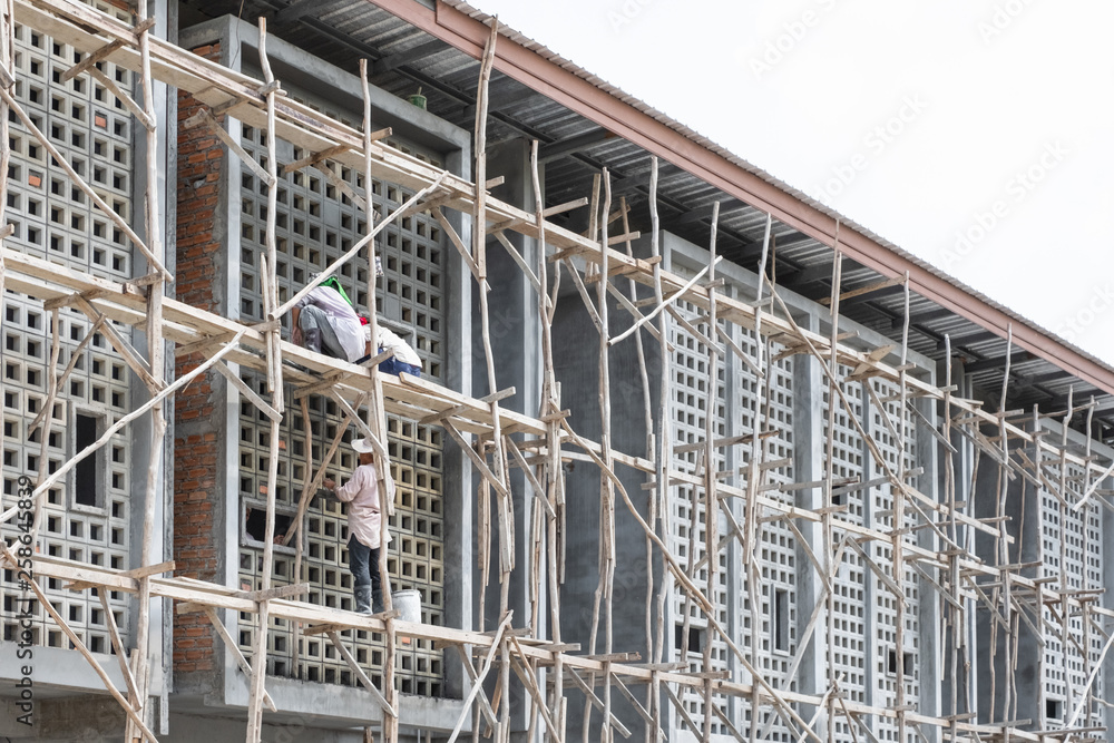 Construction workers on a wooden scaffold.