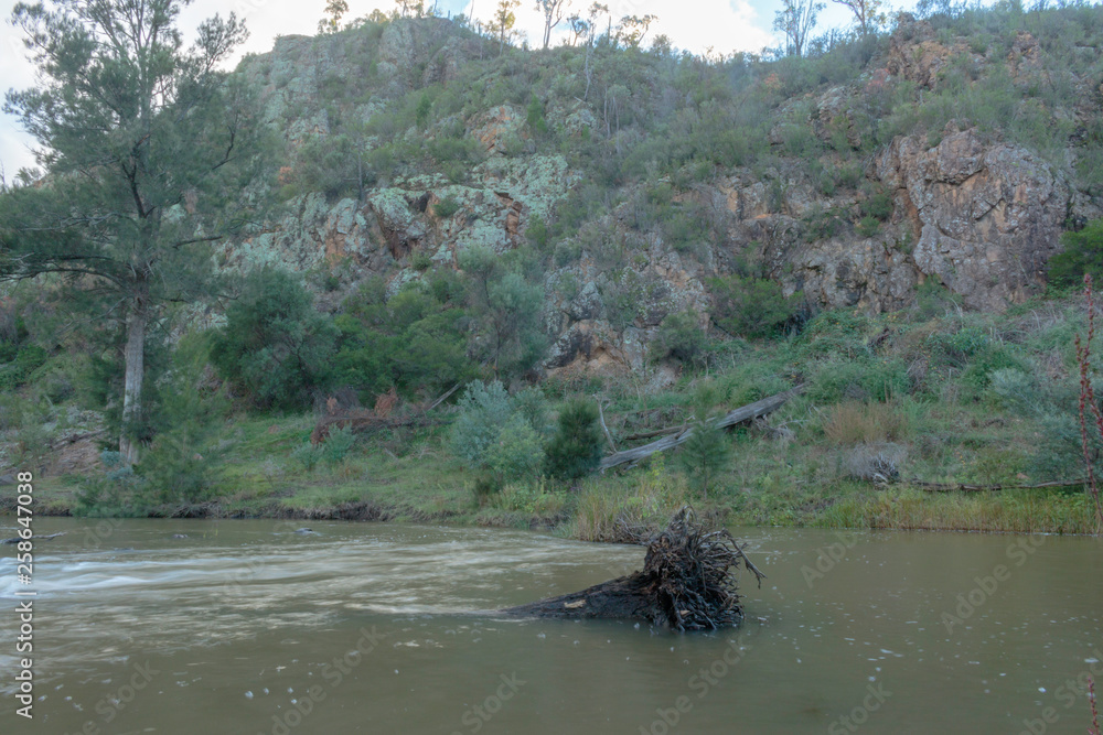 The Murrumbidgee River running past a rock wall at Casuarina Sands Reserve, Canberra, Australia during the morning of March 2019